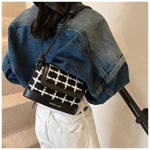 Detail of tweed crossbody bag with contrast trim and logo on a stylish model