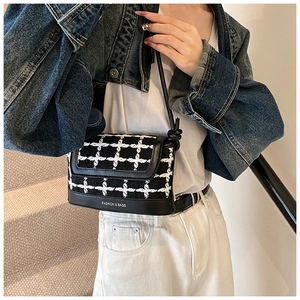 Detail of black and white tweed crossbody bag with FASHION & BAGS logo text and leather trim