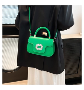 Detail of a bright green mini handbag with a sparkling square rhinestone buckle on leather