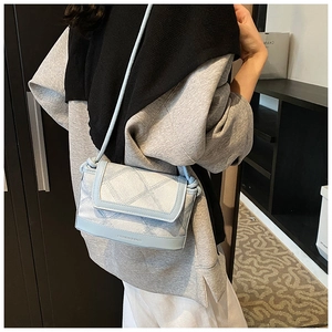 Model wearing a light blue quilted crossbody bag with denim texture and a slim strap