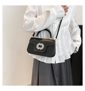 Detail of black leather handbag with rhinestone buckle and adjustable shoulder strap