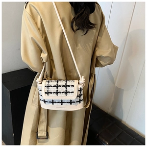 Detail view of plaid tweed and white PU leather crossbody bag with knot shoulder strap