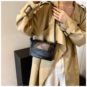 Close-up of black plaid crossbody bag worn with khaki trench coat for spring style