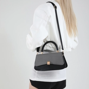 Modern black and white baguette shoulder bag with gold clasp shown on a model
