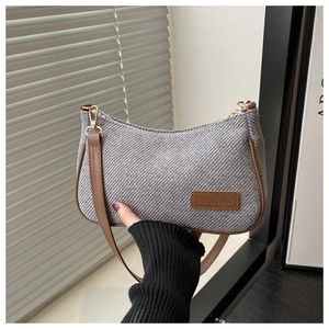 Détail du sac à bandoulière tressé gris avec garniture en cuir brun et crochets dorés