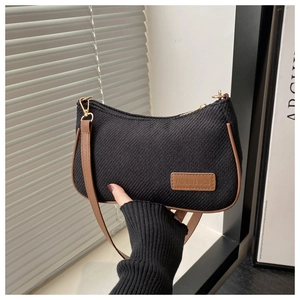 Détail du sac sous le bras en sergé noir avec garniture en cuir brun et étiquette de mode