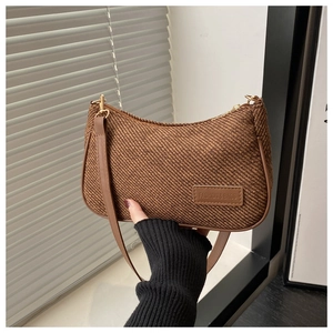 Détail de la texture tissée café et étiquette en cuir sur le sac porté épaule
