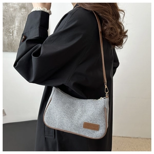 Detail of grey twill crescent bag featuring brown leather trim and fashion logo patch