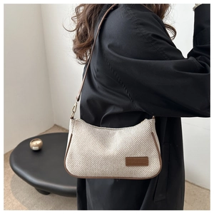 Close-up of beige woven texture shoulder bag with brown leather trim and fashion logo