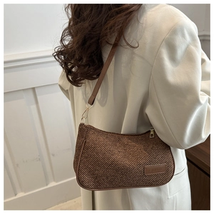 Détail du sac bandoulière tressé marron foncé avec étiquette en cuir et boucles dorées