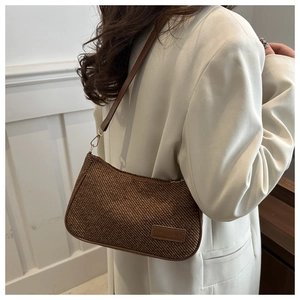 Détail de la texture tissée marron du sac porté épaule avec écusson en cuir