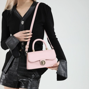 Light pink oil wax leather crossbody bag with golden ring lock shown on model