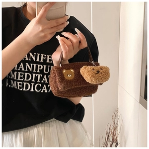 Détail d'un sac à main en peluche marron foncé avec broderie d'ours et breloque ourson