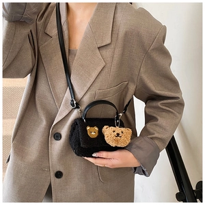 Détail du petit sac bandoulière en peluche noire avec broderie et charme d'ours
