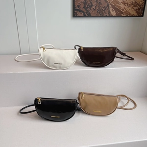 Minimalist half-moon crossbody bags in four colors displayed on a modern gallery stand