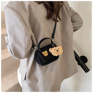 Détail du petit sac carré en fausse fourrure noire avec patch et pendentif d'ours