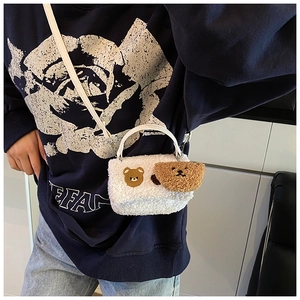 Gros plan d'un sac bandoulière en peluche blanche avec broderie ours et breloque ours 3D