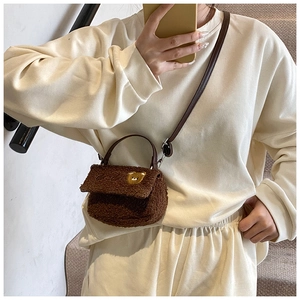 Détail du sac bandoulière en peluche marron avec emblème d'ours et sangle en cuir
