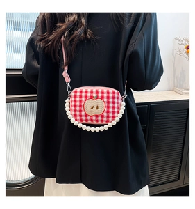 Detail of pink plaid crossbody bag with apple embroidery and pearl beaded handle