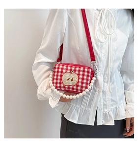 Detail of red and white checkered crossbody bag with apple embroidery and pearl handle