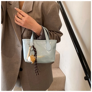 Detail of light blue glossy mini tote with creative baseball charms and gold text