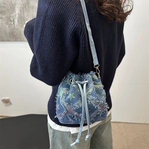 Sac seau en denim à cordon avec motifs d'étoiles et fine bandoulière porté par mannequin