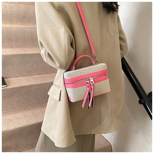 Détail du sac boîte en tissu beige et cuir rose avec zips à pompons décoratifs