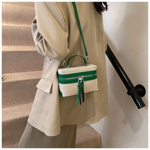 Detail van canvas box-tas met groene lederen afwerking gedragen door een model