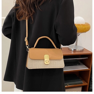 Detail of a vintage-style two-tone crossbody bag with gold buckle in home setting