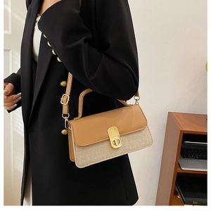 Detail of minimalist two-tone leather crossbody bag with golden twist lock on a shoulder strap