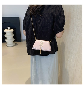 Detail of pink glossy shoulder bag with golden S logo and elegant tassel chain strap