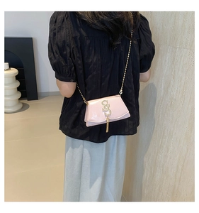 Detail view of light pink patent leather mini crossbody bag with gold SS hardware and tassel