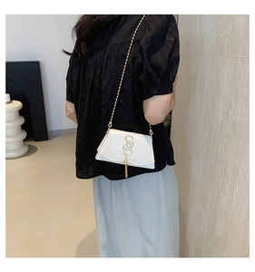Detail of off-white leather crossbody bag with golden S logo and tassel chain strap