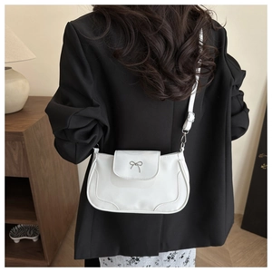Détail d'un sac à bandoulière blanc avec boucle nœud argentée sur cuir synthétique lisse