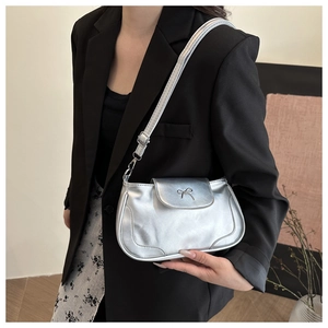 Close-up of a silver bow-knot shoulder bag worn with a black blazer for a stylish look