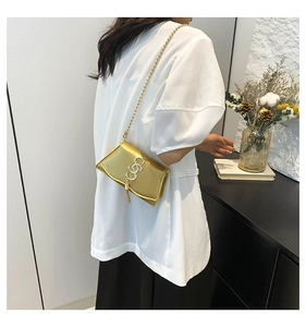 Detail of golden crossbody bag with stylish chain strap and decorative metallic tassel buckle