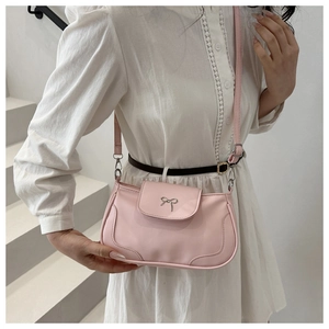 Detail of pink leather crossbody bag with silver metal bow and adjustable shoulder strap