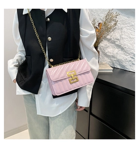Détail du sac bandoulière rose matelassé en V avec fermoir géométrique doré et chaîne