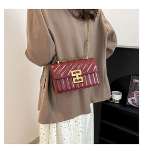 Detail of burgundy crossbody bag featuring V-shaped quilting and gold metal chain strap