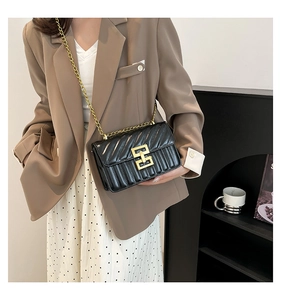Détail du sac à bandoulière en cuir noir matelassé avec chaîne dorée et fermoir métal