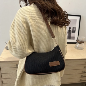 Sac bandoulière noir en forme de croissant avec bordure en cuir marron et sangle réglable