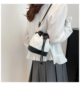 Detail view of a quilted contrast drawstring bucket bag worn over the shoulder