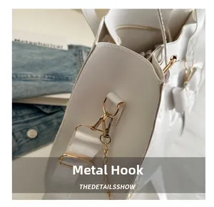 Detailed view of the gold-toned metal hook and chain on a white bow tote bag