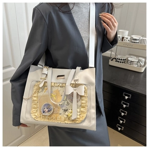 Detailed side view of a white Ita bag with yellow lace trim and transparent front window