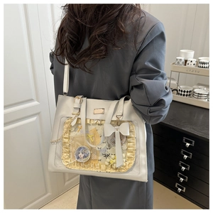 Detailed view of white ita bag with clear window, ruffle trim, and bow accessory