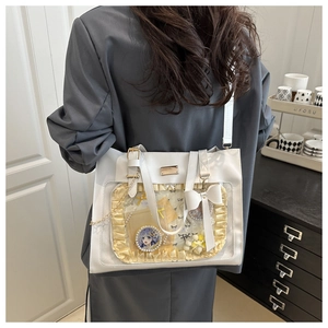 White ita bag tote with clear PVC window and yellow ruffles showing badges and charms