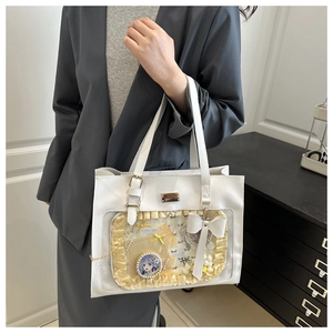 Detail of white ita bag showing transparent PVC window with badges and decorative ribbon
