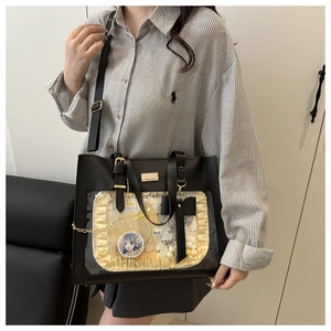 Close-up of black ita bag with transparent window, yellow lace lining and bow detail