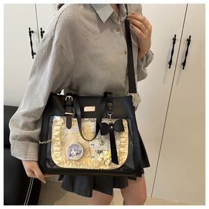 Detail of black ita bag with clear window featuring decorative pins and lace lining