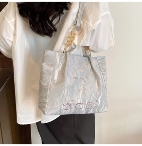 Detail of light gray tote bag with wrinkled texture, artistic print, and chain handle